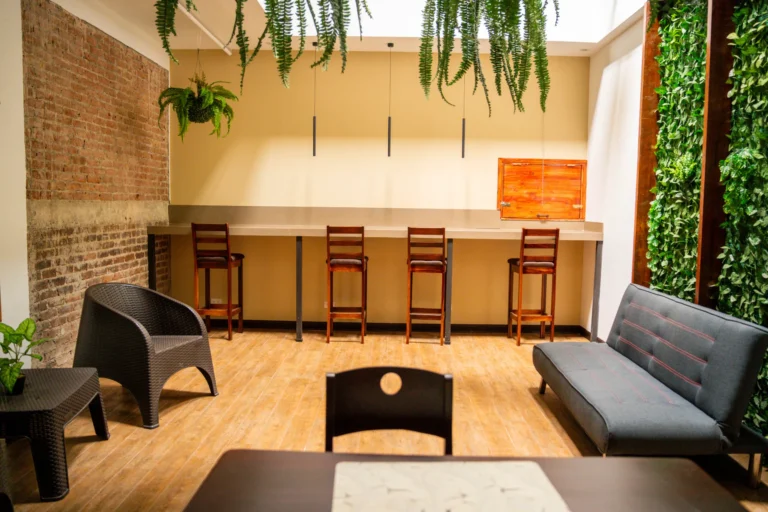 Shared coworking lounge with brick wall, hanging plants and bar seating at Candó Living
