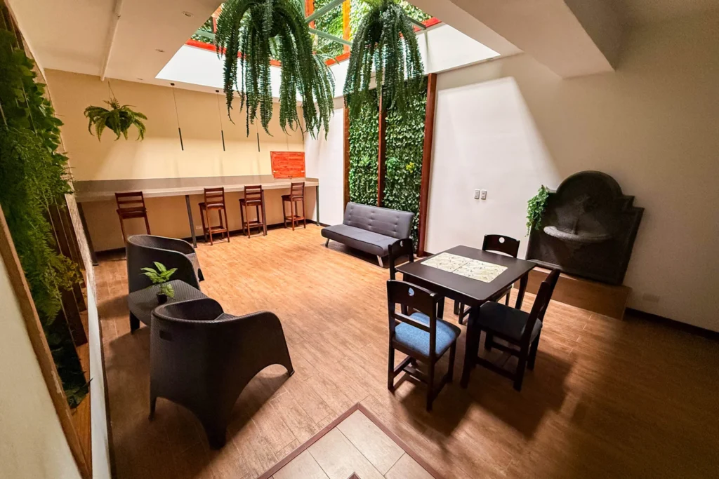 Common lounge with sofa, tables and vertical garden at Candó Living in San José
