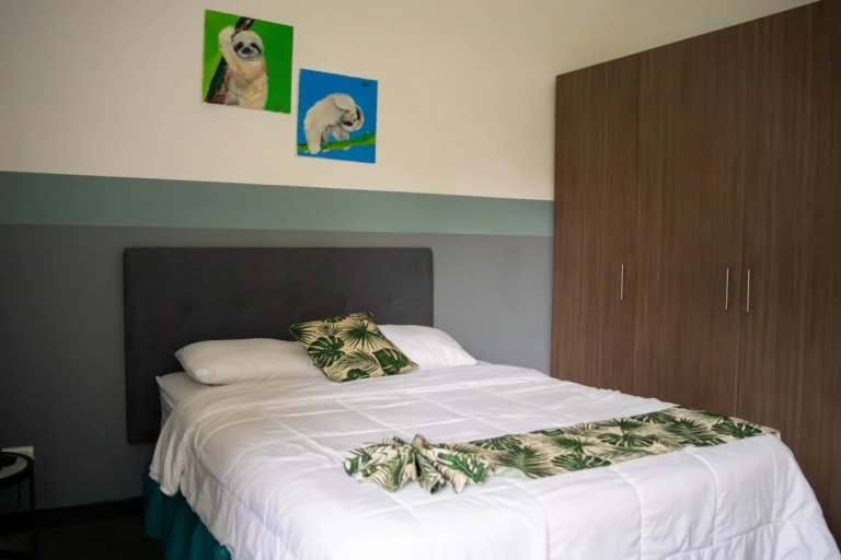 Comfortable apartment bedroom with queen bed and sloth artwork at Candó Living, San José